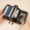 A hand holds an open brown PU leather double zipper wallet filled with various currency notes and coins.