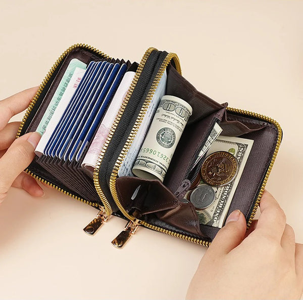 A hand holds an open brown PU leather double zipper wallet filled with various currency notes and coins.