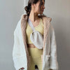 A woman wearing a yellow crop top and pants, accessorized with an ivory fleece crossbody belt bag.