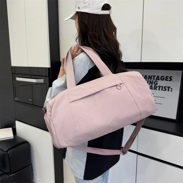 A woman holds a pink Oxford gym duffel bag with a wet/dry compartment in a modern setting.
