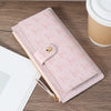 A pink elegant folding multi-card wallet with a zipper and gold hardware resting on a wooden surface.