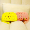 A yellow silicone coin pouch and an orange silicone coin pouch resting on a light-colored sofa cushion.
