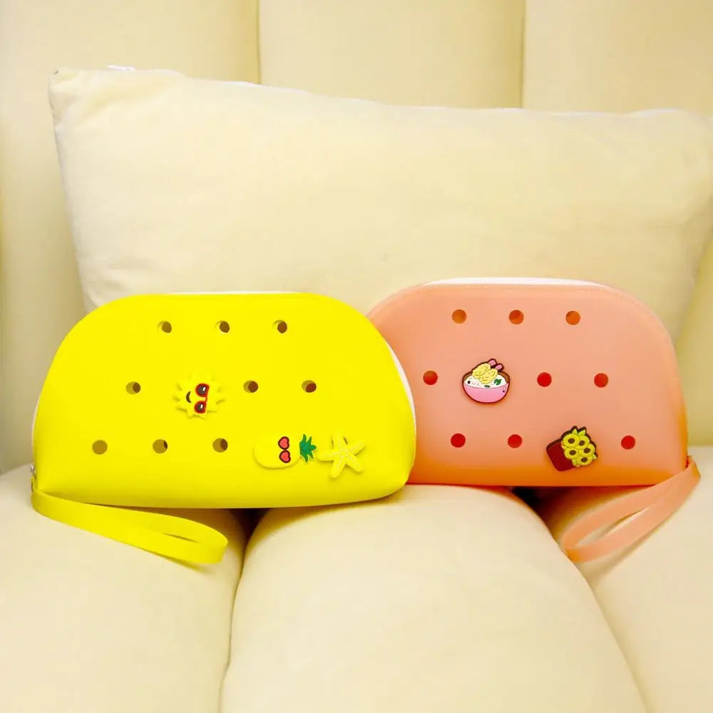 A yellow silicone coin pouch and an orange silicone coin pouch resting on a light-colored sofa cushion.