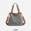 Front view of a gray canvas tote bag with brown leather straps.