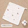 A white muslin baby burp cloth towel with small rose gold moon patterns is shown on a beige textured surface.