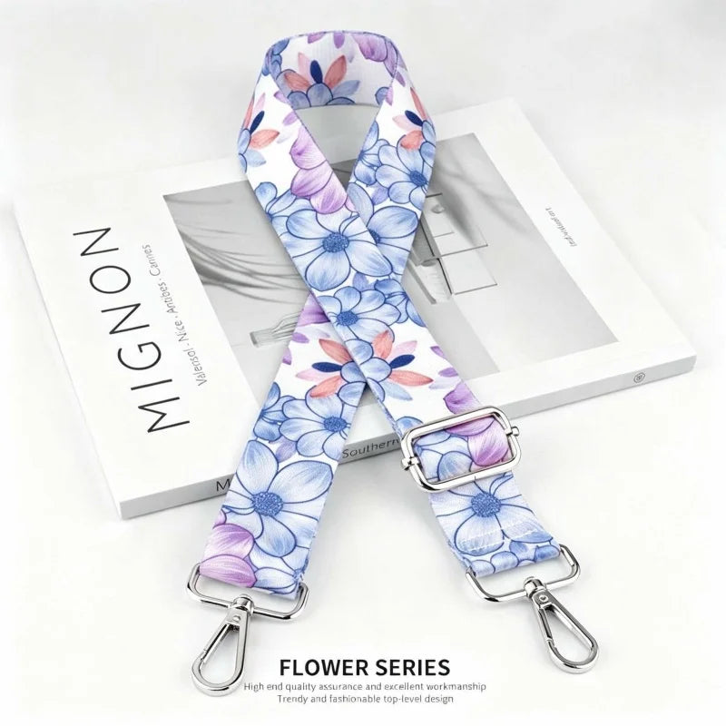 A floral patterned nylon shoulder strap featuring blue and purple flowers displayed on a white box.