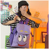 A person is holding a purple Dora The Explorer cartoon flannel backpack in front of them.