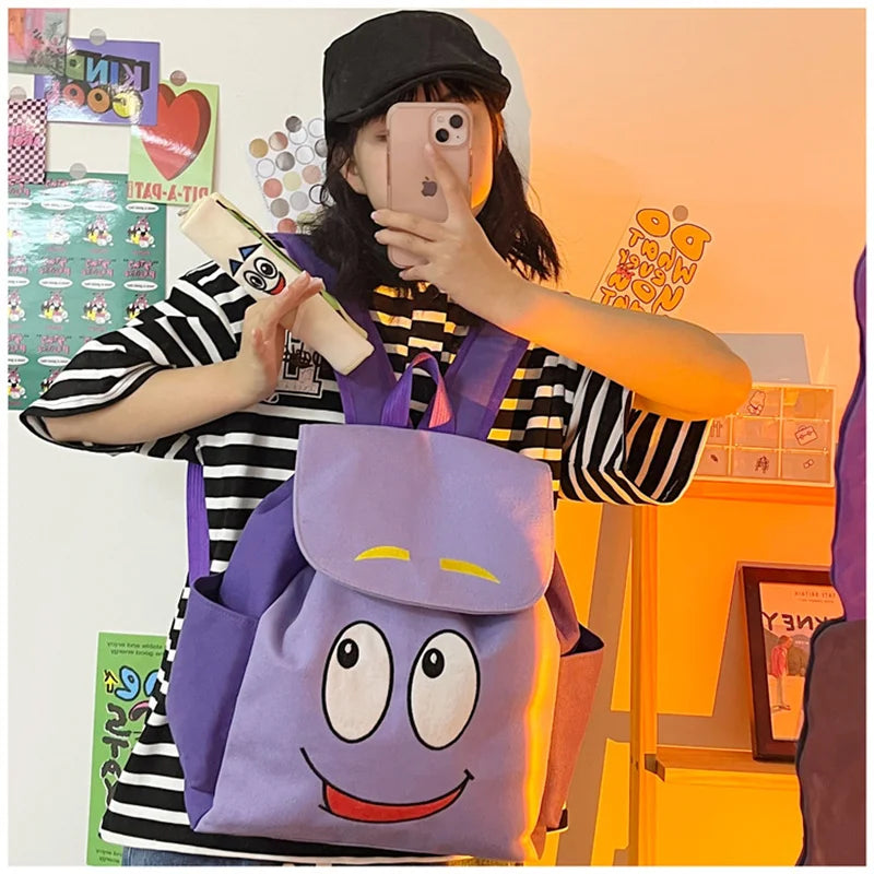 A person is holding a purple Dora The Explorer cartoon flannel backpack in front of them.