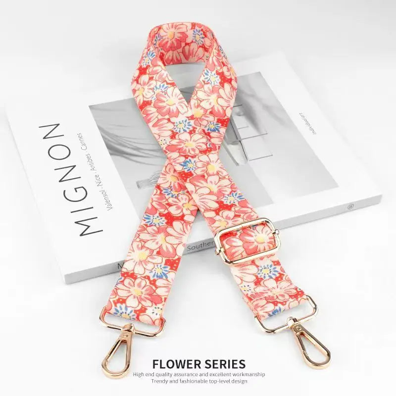 A pink floral patterned nylon bag strap is displayed on a white box.