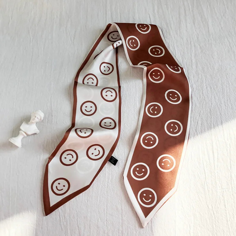 Foulard de cheveux en soie marron avec motifs de smiley blancs, présenté sur fond blanc.