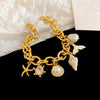 Gold chain bracelet featuring ocean pearl charms including a starfish, shell, and clam accents.