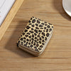 A small leopard print double zipper wallet resting on a wooden surface.
