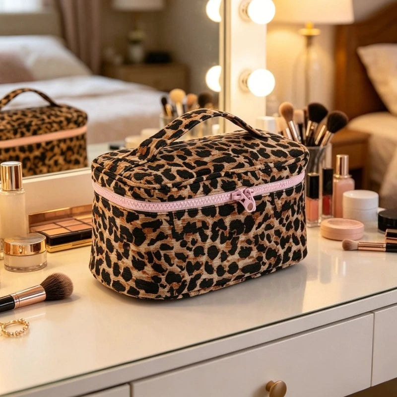 Bolso de maquillaje para viajar con estampado de leopardo y ribete rosa sobre un tocador blanco.