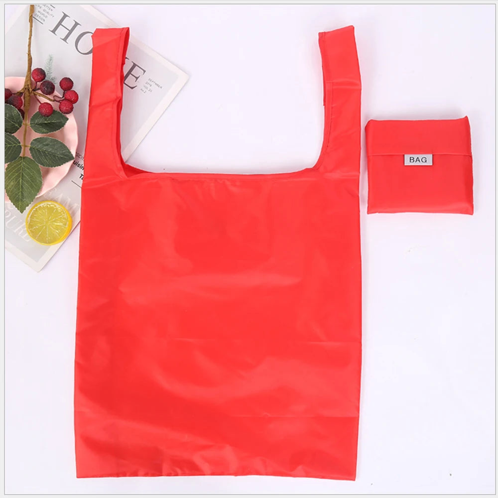 A bright red eco-friendly foldable shopping bag next to a small red bag.