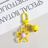 Yellow resin flower keychain with a gold hook and purple center, displayed on white paper.
