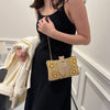 A woman wearing a black dress holds a gold rhinestone evening clutch bag.