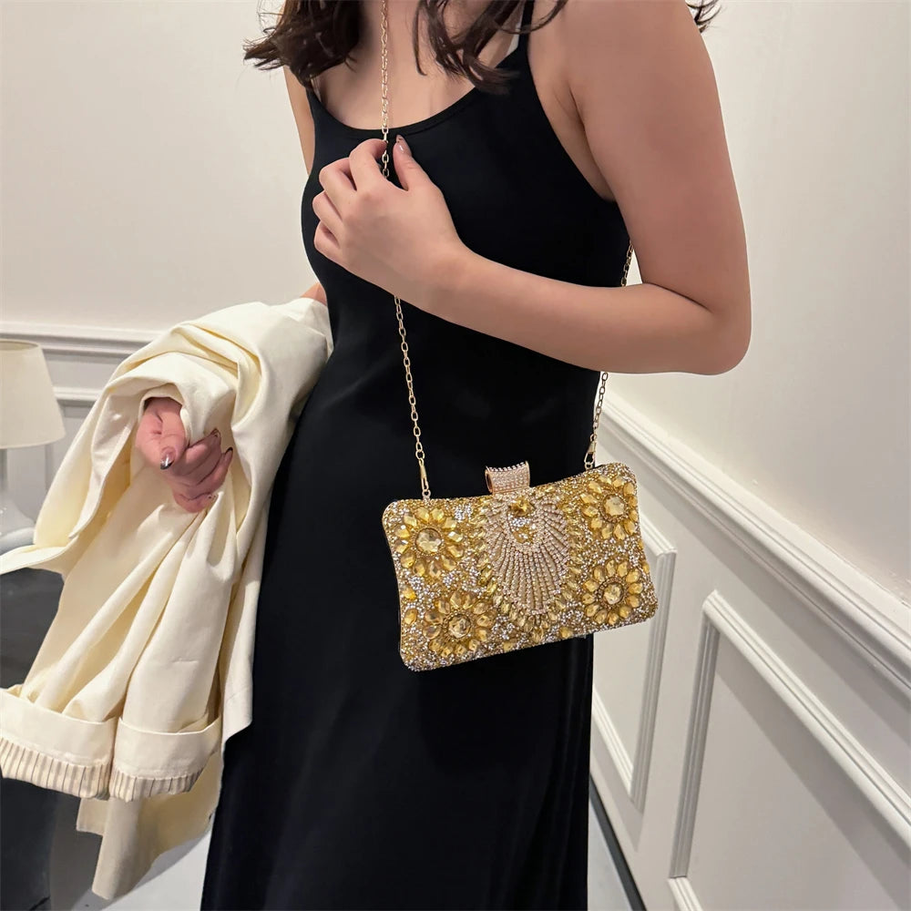A woman wearing a black dress holds a gold rhinestone evening clutch bag.