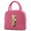 A pink insulated canvas lunch bag featuring a gold letter 'T' and floral embroidery.