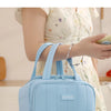 Una bolsa térmica acolchada azul claro para el almuerzo, sostenida por una mujer con un vestido floral blanco.