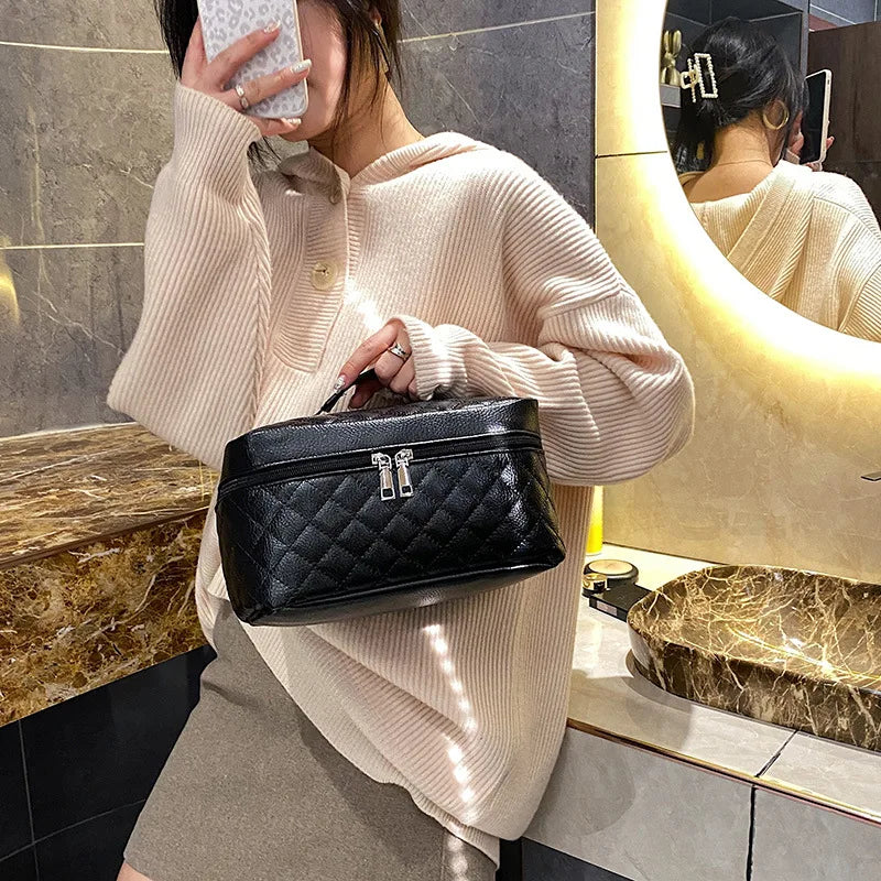 A woman wearing a beige sweater holds a black quilted makeup storage pouch in a brightly lit store setting.