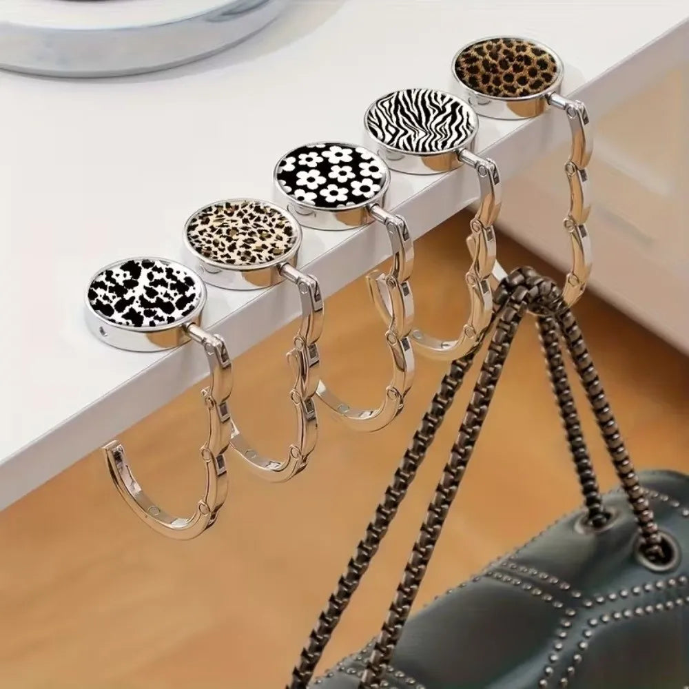 A set of round metal bag hangers with leopard and zebra print tops displayed on a white surface.