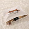 A beige fabric storage bag with a brown sausage dog pattern is shown open, containing makeup brushes.