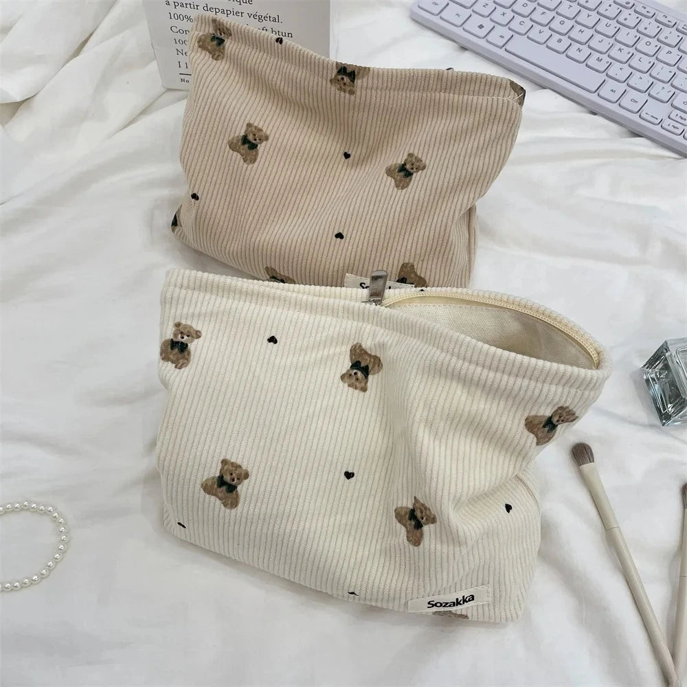 A beige corduroy clutch bag with a small brown animal print is displayed on a white surface.