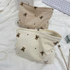 A beige corduroy clutch bag with a small brown animal print is shown on a white surface.