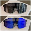 Un par de gafas de sol para ciclismo azules con monturas oscuras exhibidas sobre una superficie blanca.