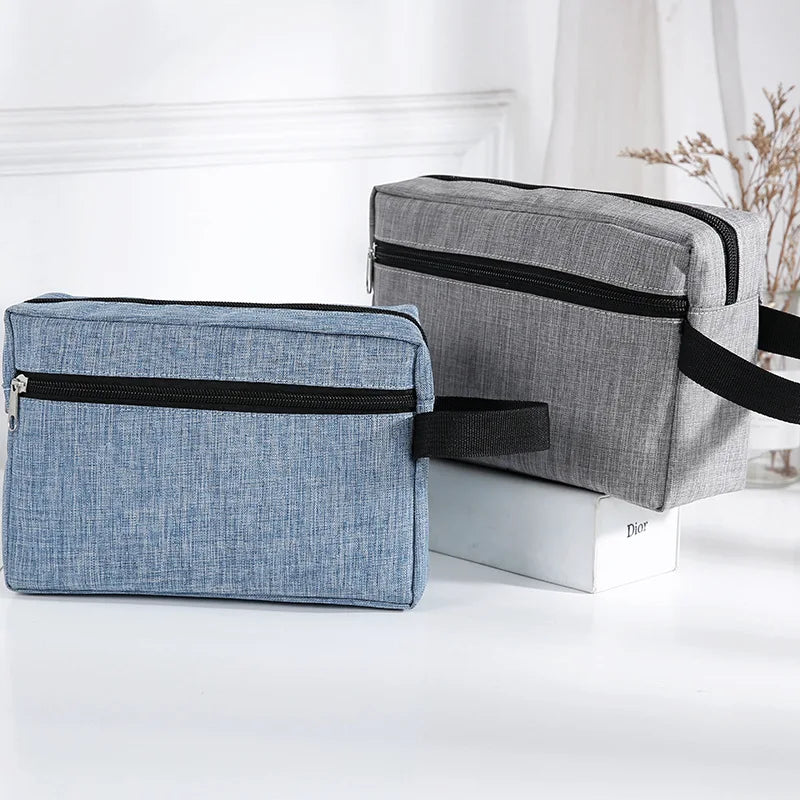 Gray and blue fabric cosmetic bags with black trim displayed on a white surface.