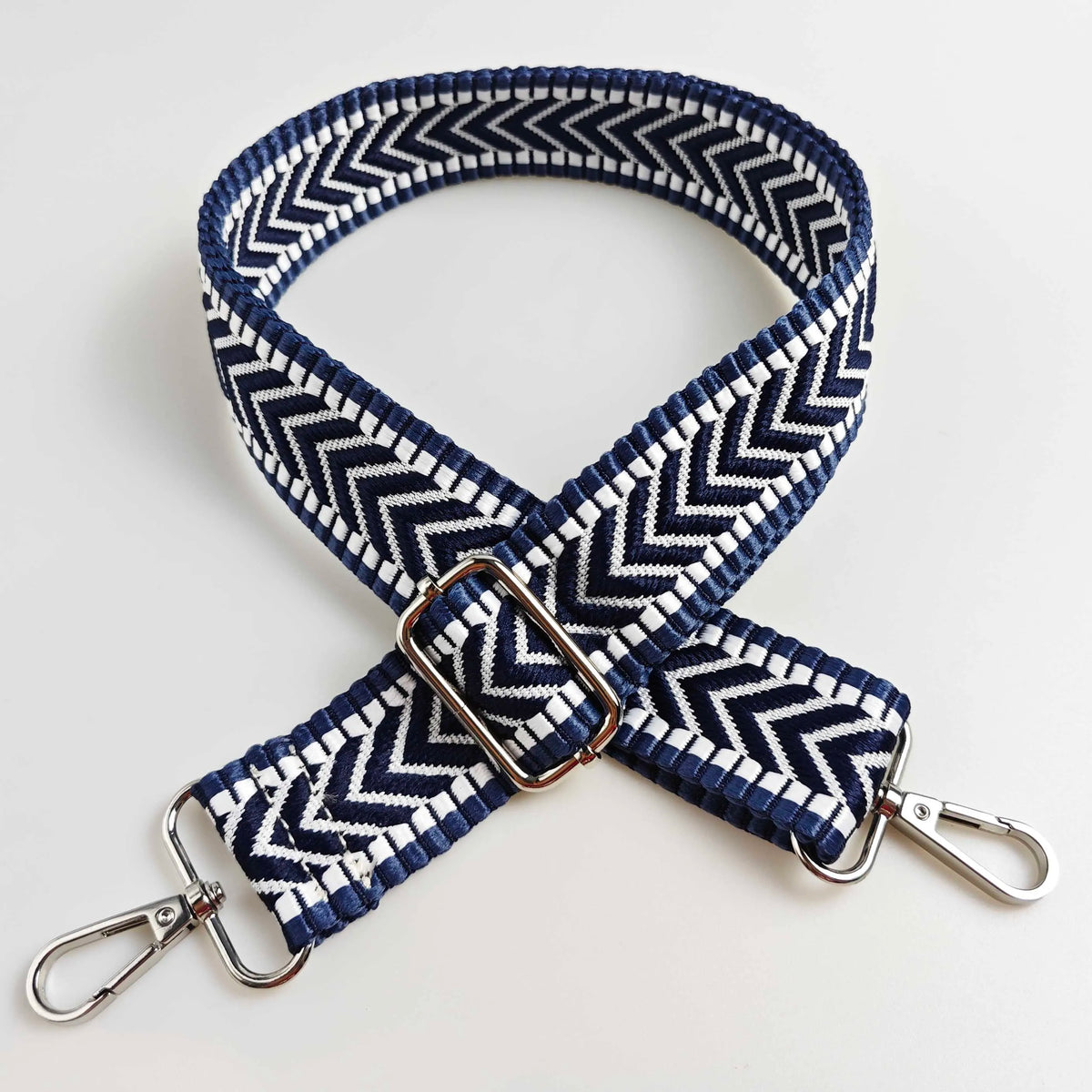 A navy blue and white patterned adjustable handbag strap with a silver buckle.