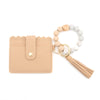 A beige silicone bead bracelet is displayed next to a light tan leather card holder with a tassel.