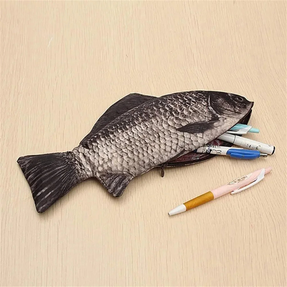 A black fish-shaped pencil case and coin purse resting on a light wooden surface next to colored pencils.