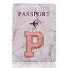 Una funda de pasaporte de imitación de cuero rosa con una inicial P dorada y un ícono de avión.