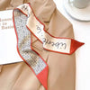 Un blazer beige présente un élégant foulard de cheveux en soie florale à motif géométrique et accents rouges.