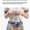 A woman holds a tan nylon dumpling crossbody bag against her torso, featuring brown leather handles and white striped top.