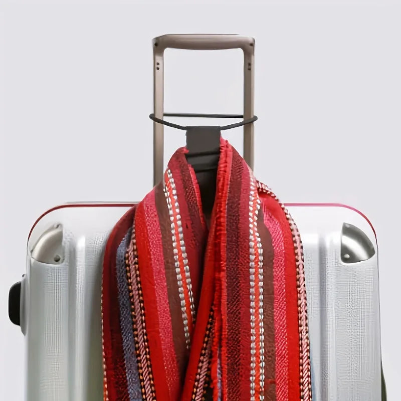 A red and striped scarf is draped over a silver suitcase with a brown strap visible.