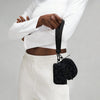 A person wearing a white top and pants holds a black nylon zipper wristlet pouch with a chain.
