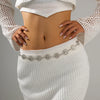 A woman wearing a white knitted top and skirt, displaying a vintage gold plated sunflower smiley face waist chain.
