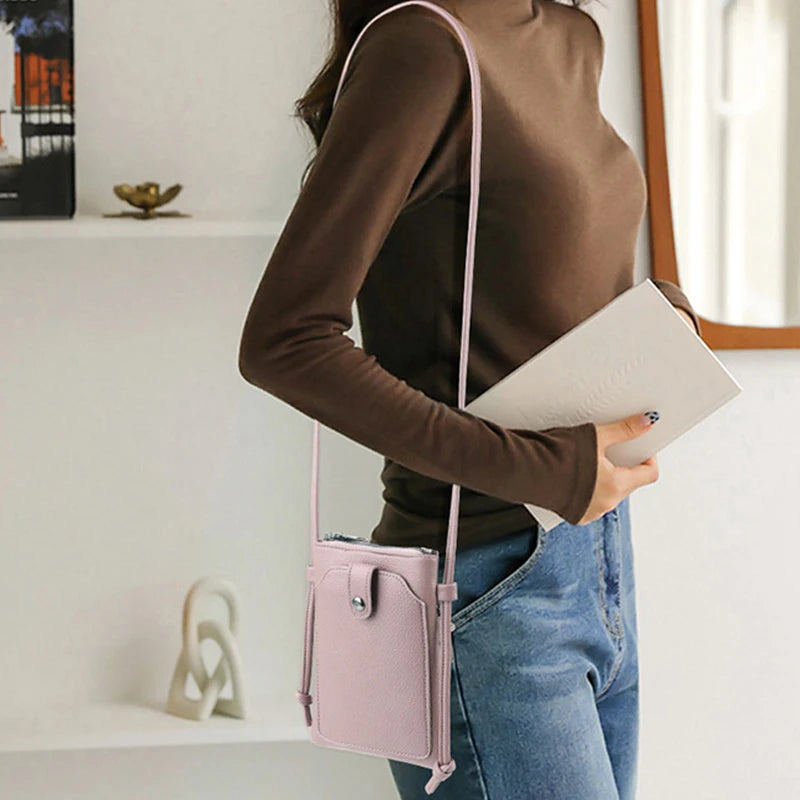 A woman wearing a brown top holds a pink compact PU leather crossbody bag and a notebook.