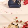 Portefeuille-clés en PVC luxueux couleur or, bleu marine, posé sur un fond clair avec des fleurs rouges.