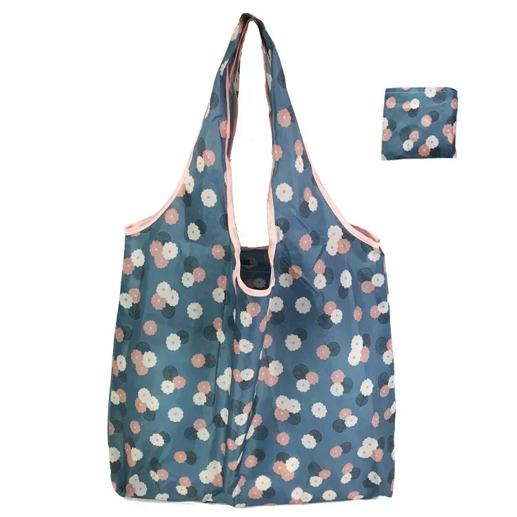 A light blue floral print tote bag with pink accents shown in a vertical orientation.