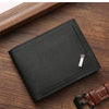 A black slim leather wallet with a silver money clip resting on a wooden surface.