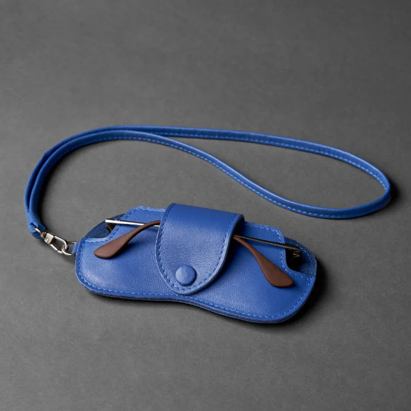 A blue PU leather eyewear storage case with a flap and leather cord is shown against a dark gray background.