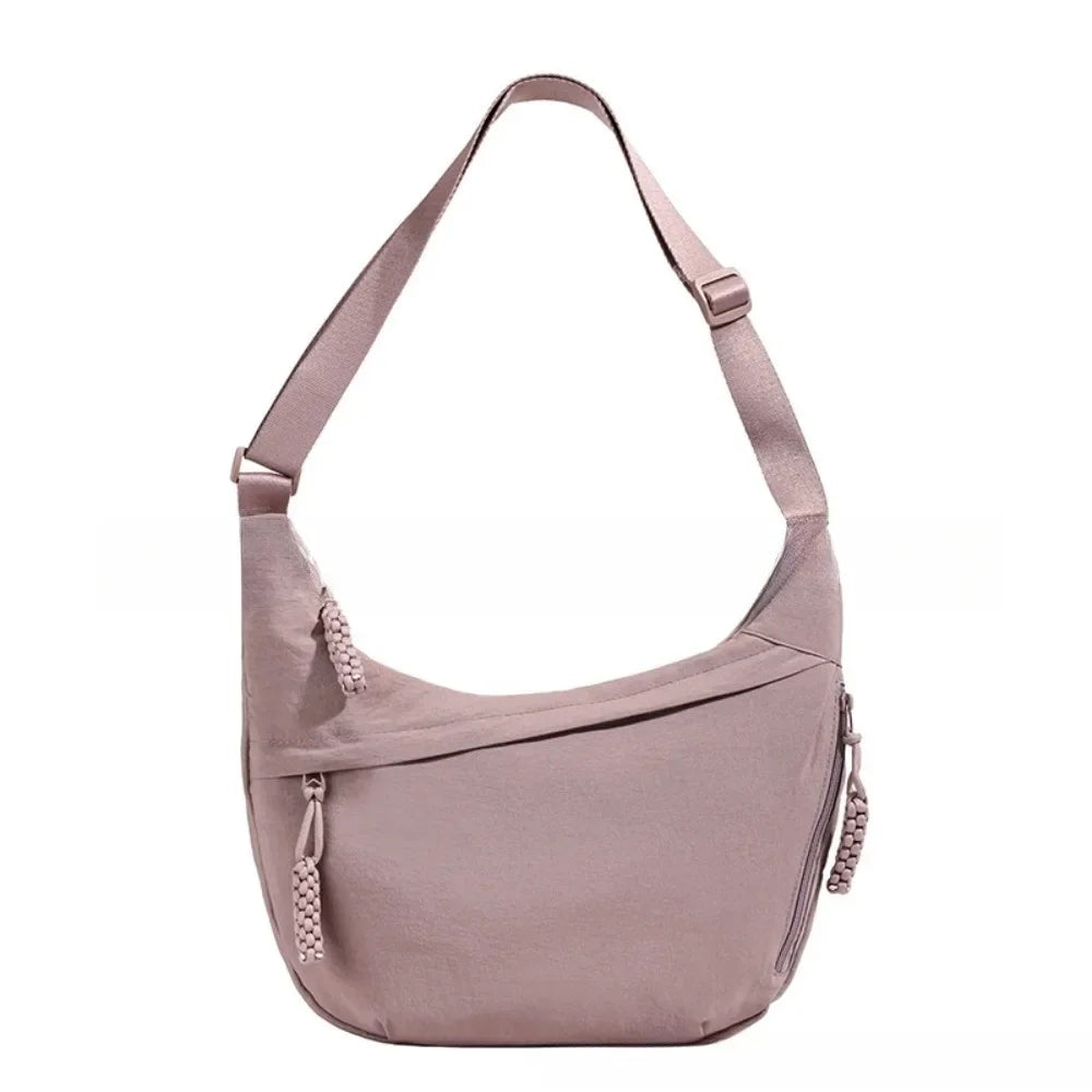 A light mauve canvas crossbody bag shown from the front.