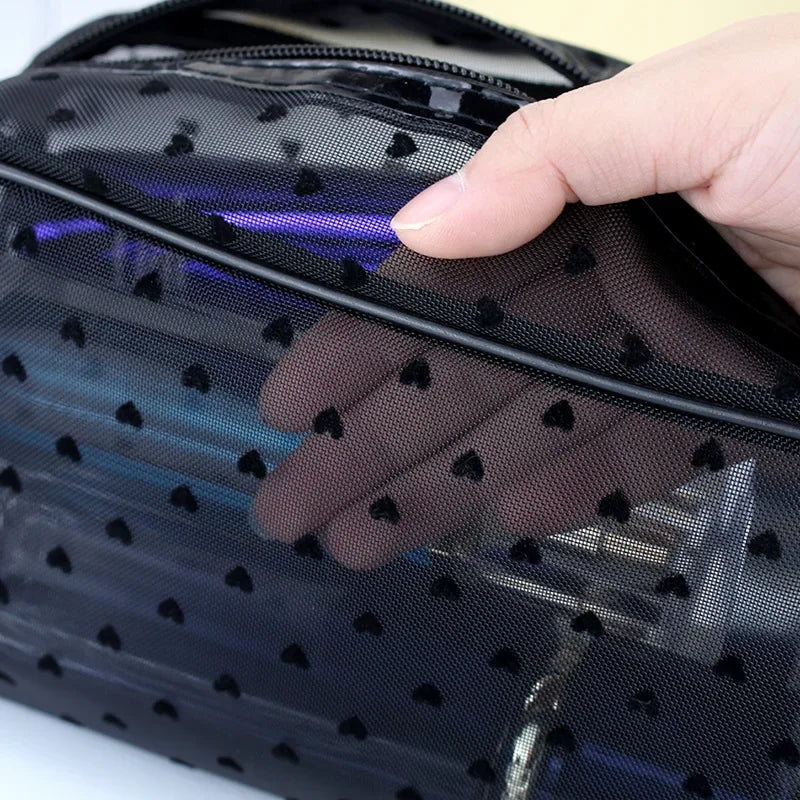 A hand is opening a black mesh transparent makeup storage bag, revealing a purple glow inside.