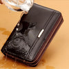 A black leather long zipper wallet clutch being filled with liquid on a light brown surface.