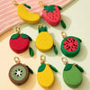 A collection of fruit-shaped PU leather coin purse keychains in red, yellow, and green colors.