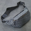 Pochette de taille designer gris foncé à motif avec une sangle noire, sur fond gris.