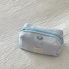 Light blue striped cotton toiletry pouch with a zipper and a small floral embellishment